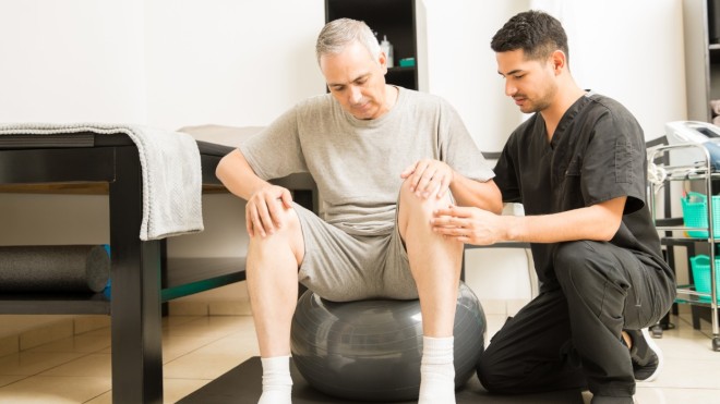 A physiotherapy practitioner works with a older gentleman on mobility exercises