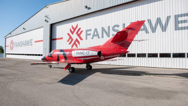 A red and white jet, marked "FANC-17" and "Fanshawe," sits on the tarmac in front of the Aviation Centre, part of Fanshawe College's London Campus.
