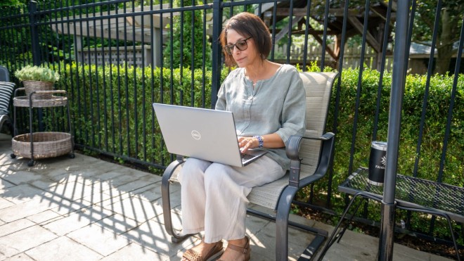 Person sitting outside in a chair on a laptop.