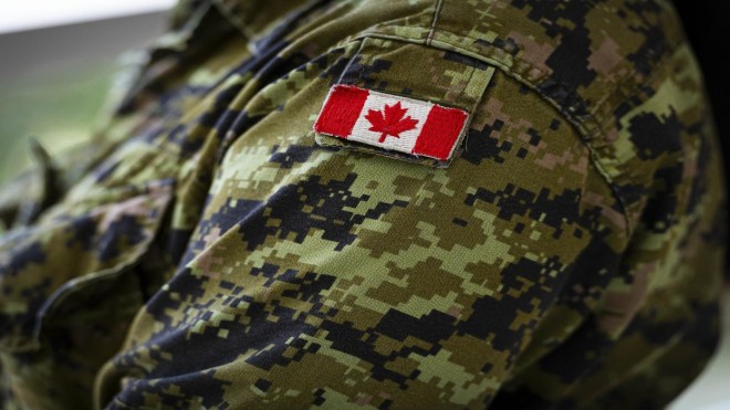 A close-up of a camouflage jacket with a Canadian flag patch on the upper arm.