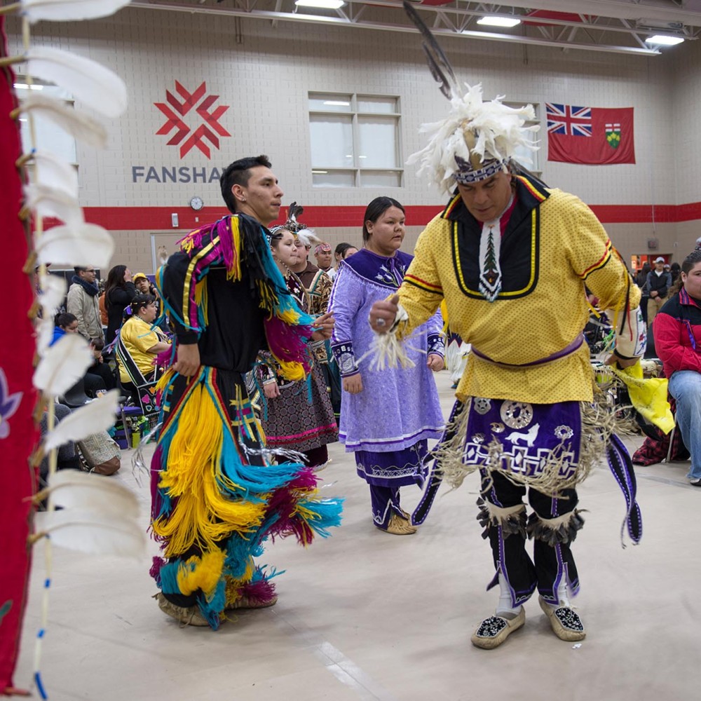 Two indigenous dancers in front of crowd