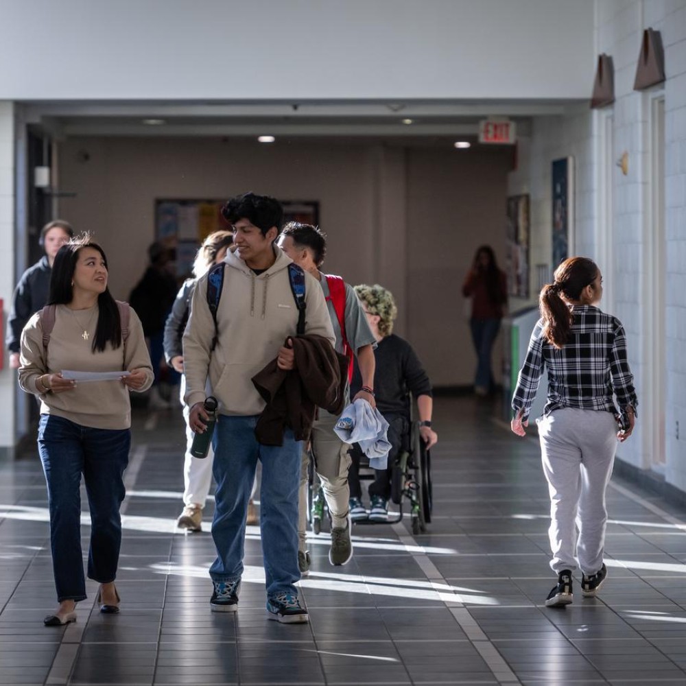 Students walk through a hallway at Fanshawe College's London Campus, with a fire extinguisher visible on the wall.