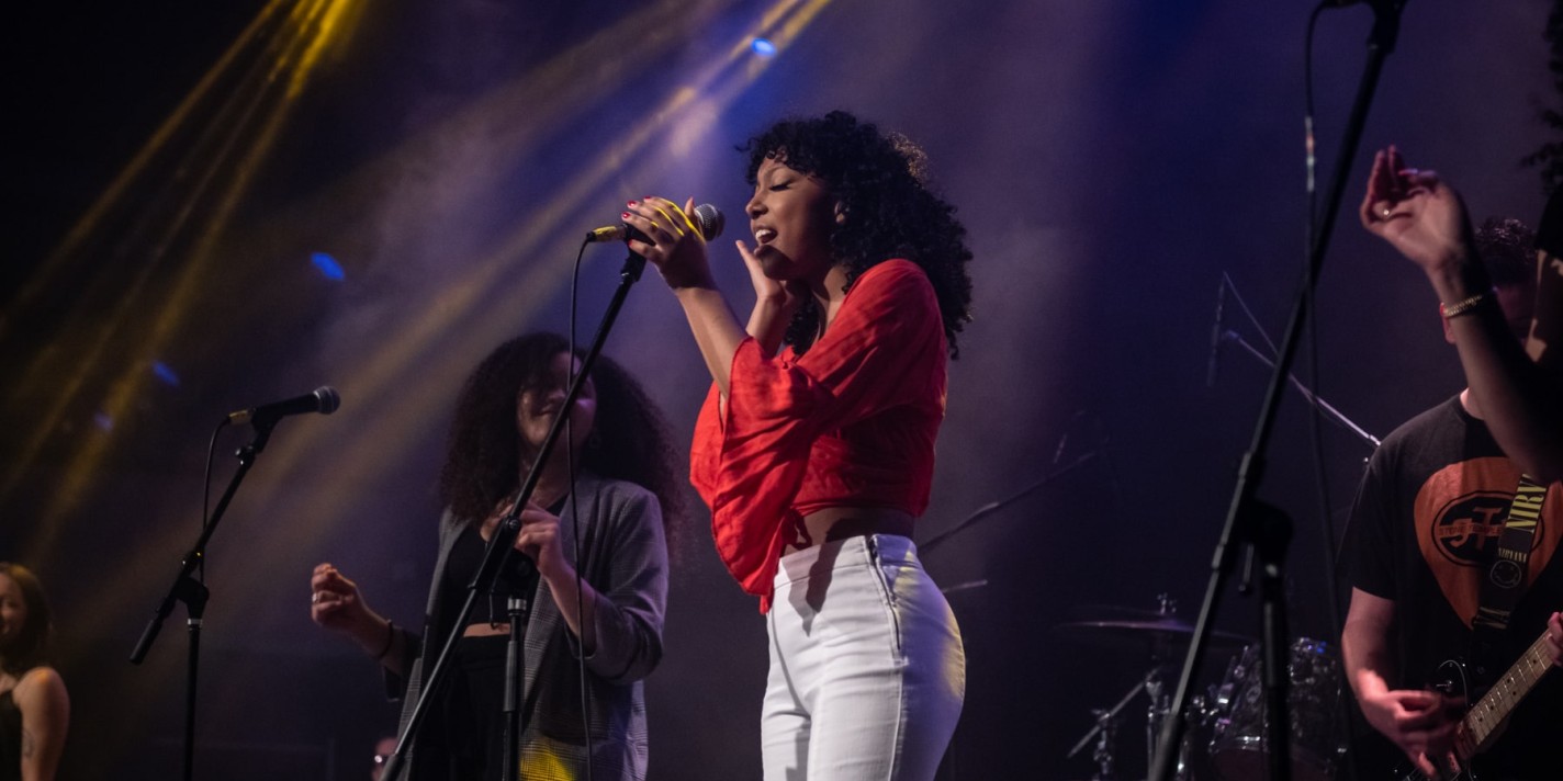 student sings on stage at Share the Land