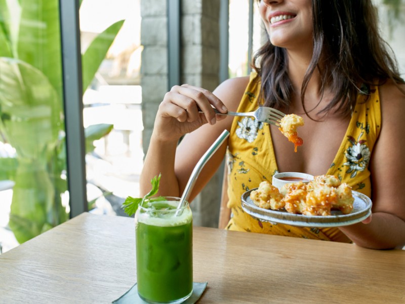 woman eating an organic plant-based cauliflower meal for vegetarians and drinking green smoothie