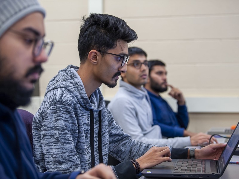 Technical systems analyst student sits looking at laptop