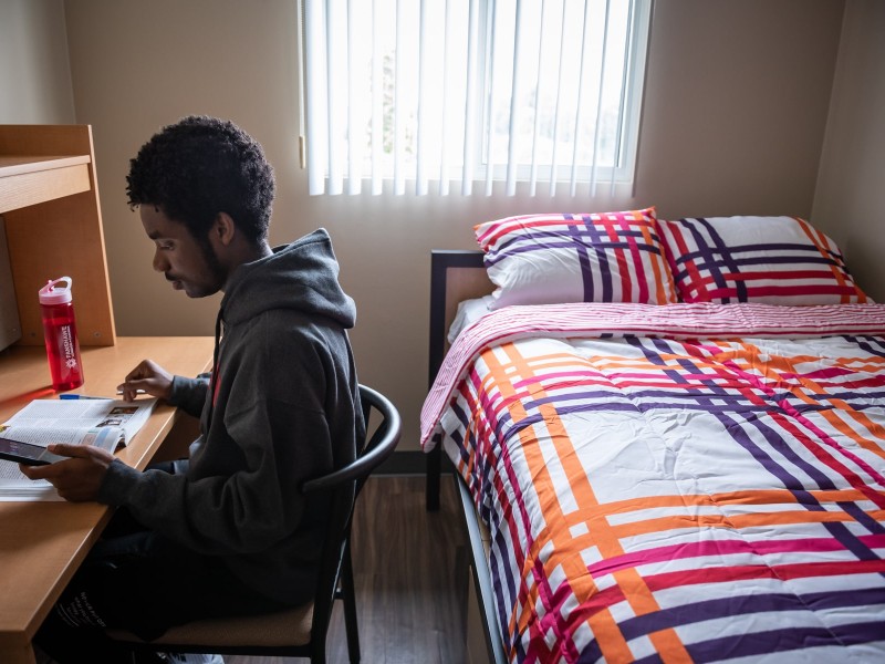 student sitting in residence room studying during reading week