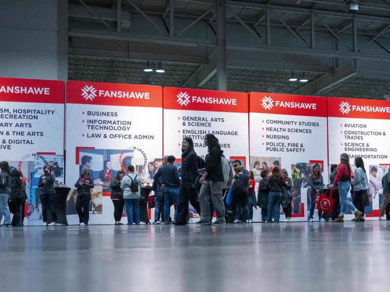 prospective students explore fanshawe programs in front of signs for areas of study