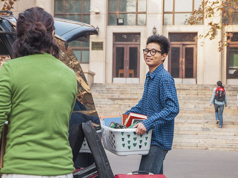 A new student carriers his belonging into residence. 