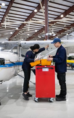 Two Aviation Technician Avionics Maintenance students working in front of airplane in Jazz Hangar at Fanshawe College
