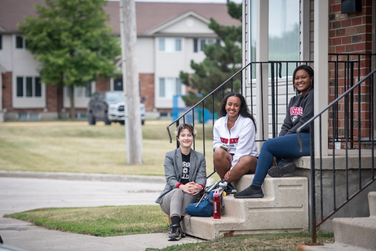 students sitting on townhouse steps and smiling