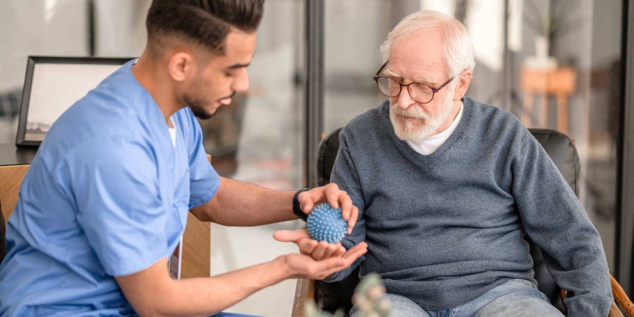 A physiotherapy practitioner works with an elderly patient on dexterity. 