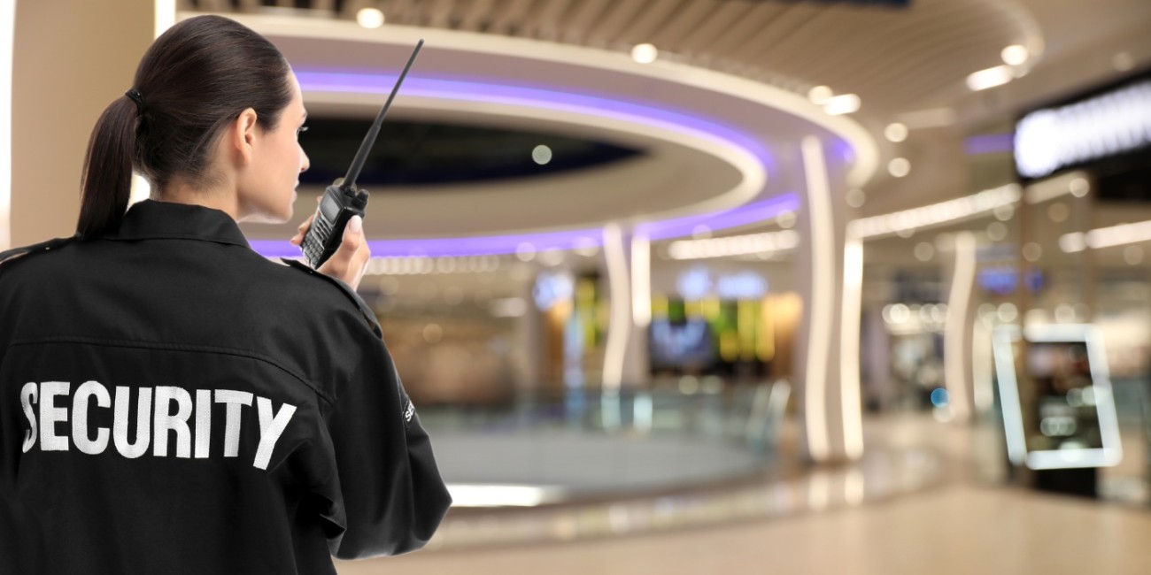 A security guard communicates over radio from the inside of a shopping mall.