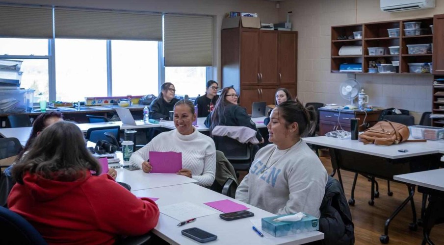 groups sit at tables, engaged in the Paswe'aatigook Anishinaabemowin Language Immersion program