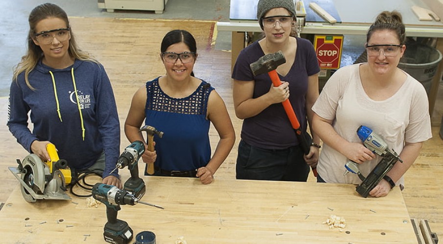 Female students working in carpentry shop with woodworking equipment