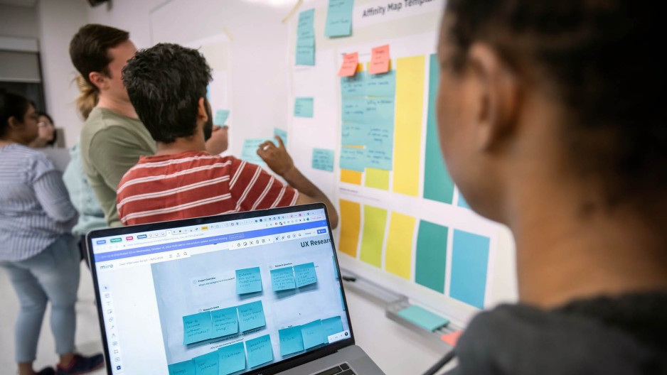 Students using post-it notes and a laptop to plan a project