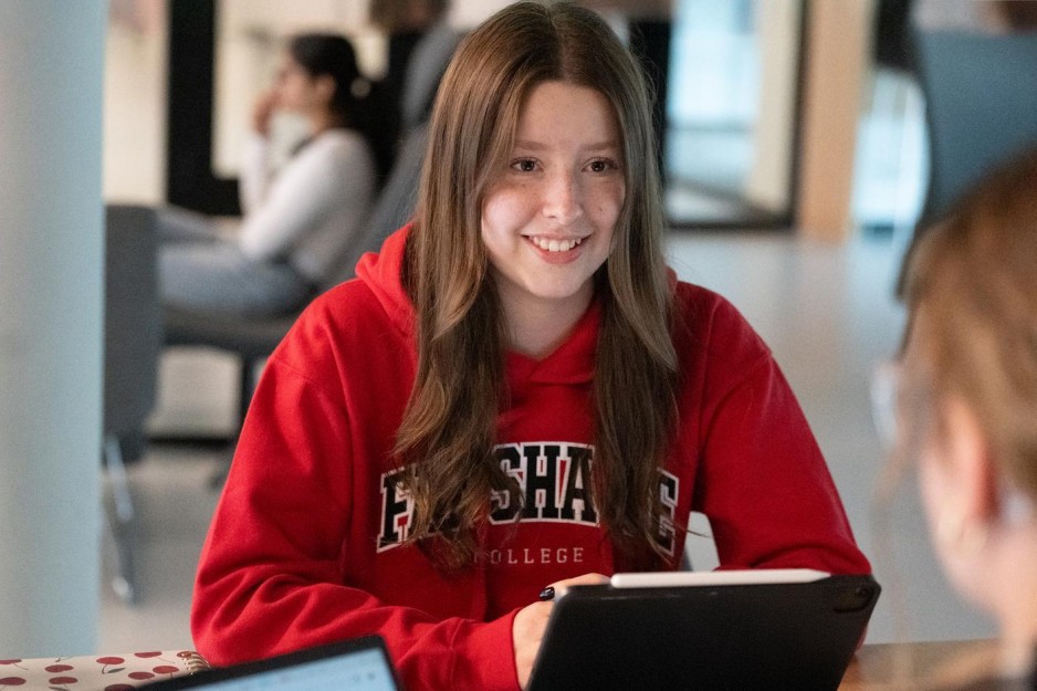 At Fanshawe College's London Campus, a student wearing a Fanshawe College hoodie smiles while working on a tablet.