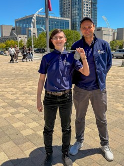 Two people in “Skills Competitions Team Ontario” shirts stand outside, one holding up a silver medal.