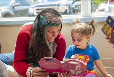 Early childhood educator reading to toddler in daycare setting