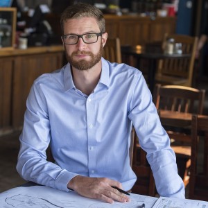 Alex Waffle sits at table with environmental design paperworks
