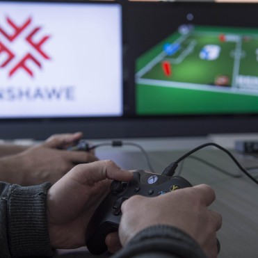 Hands holding an xbox controller with the screen in the background