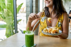 woman eating an organic plant-based cauliflower meal for vegetarians and drinking green smoothie