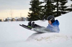 Child sledding over a ramp while wearing a helmet