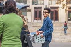 A new student carriers his belonging into residence. 