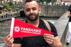 Omar Hachem holds Fanshawe Banner in Belgium