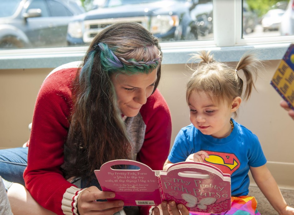 Early childhood educator reading to toddler in daycare setting