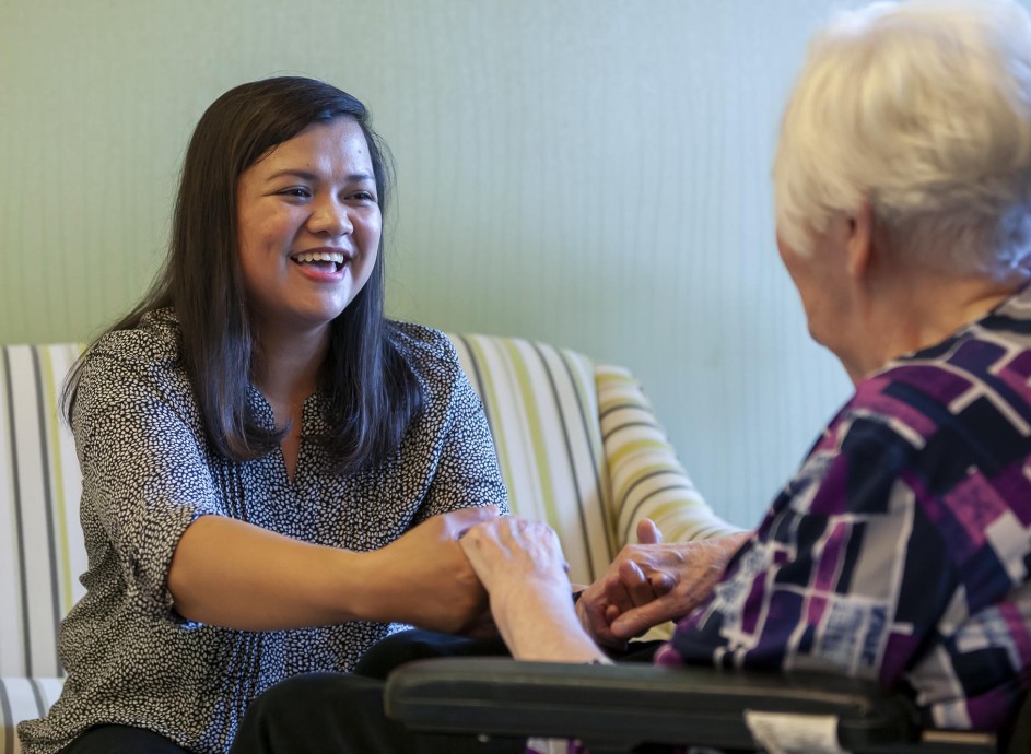 Nursing care worker smiling and interacting with elderly woman