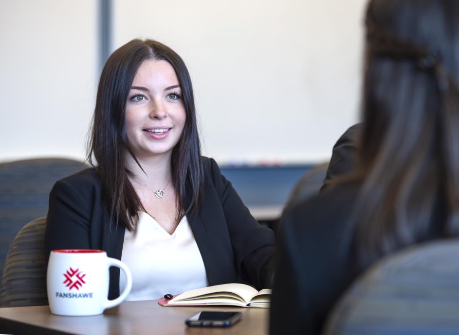 Fanshawe business student, sitting at conference table and collaborating with other students