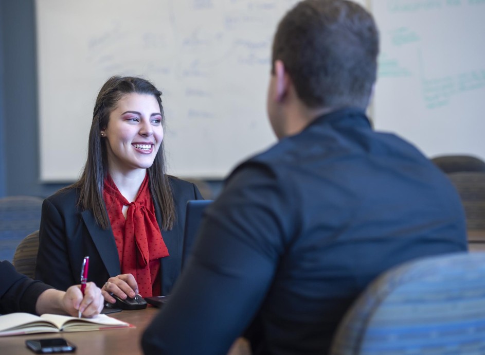 Business student smiling while sitting at conference table and collaborating with other students