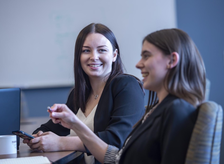 Two smiling Fanshawe business students, collaborating in a conference room