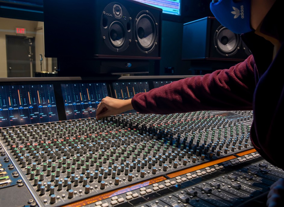 Student working on sound board in a recording studio