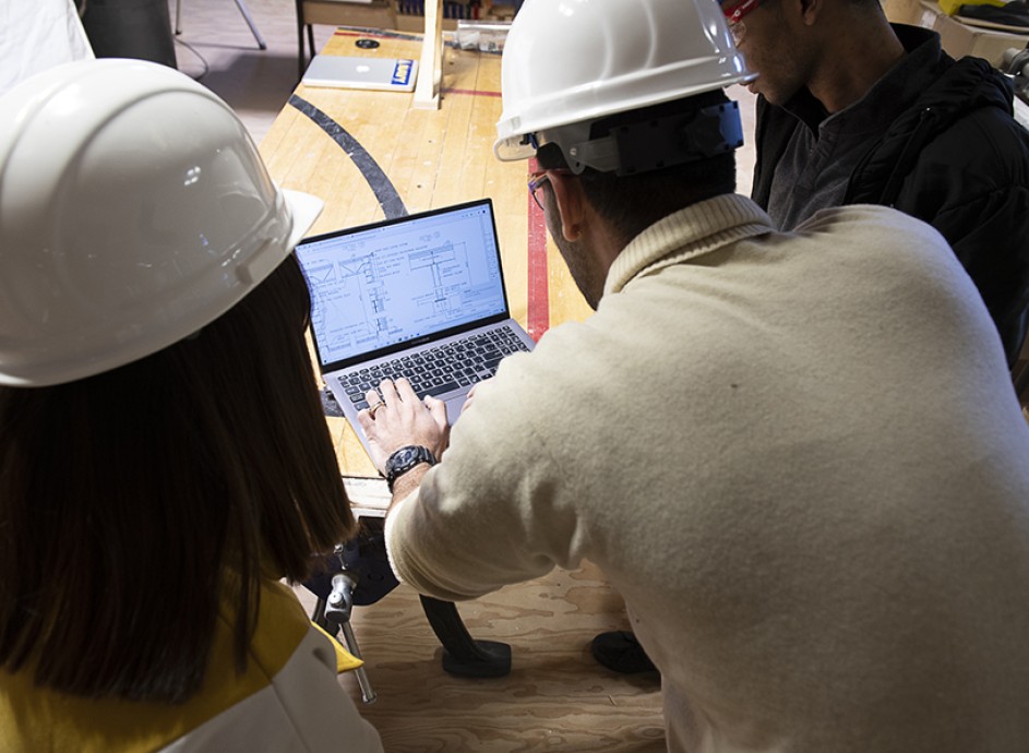 Three Construction Management students working over a laptop