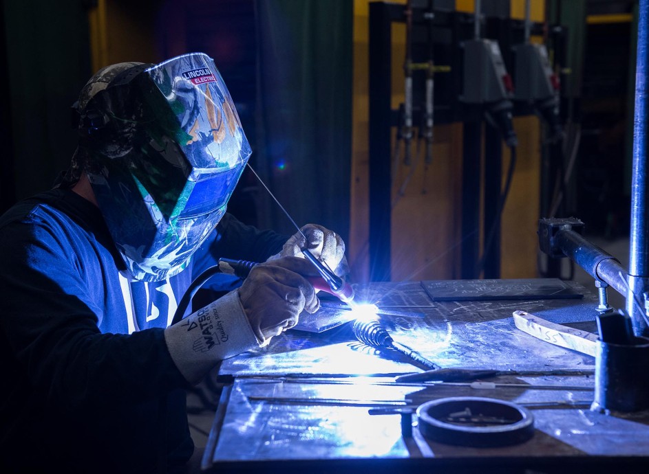 Welding student with helmet on and sparks flying