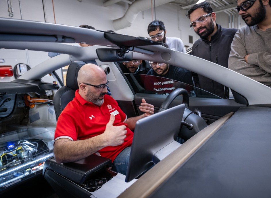 A Fanshawe instructor speaks to students while seated in a Tesla. 