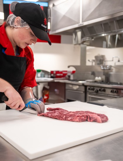 A person cutting meat in a kitchen.