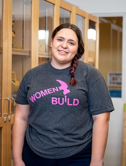 A female trades worker stands in a construction lab.