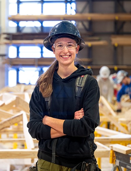 A female carpenter stands in a construction shop.