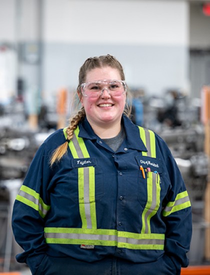 A female mechanic stands in an auto shop.