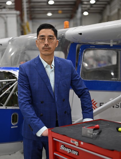 Photo of Shulin Lyu wearing a blue suit and pushing a red tool cart in front of a small engine aircraft