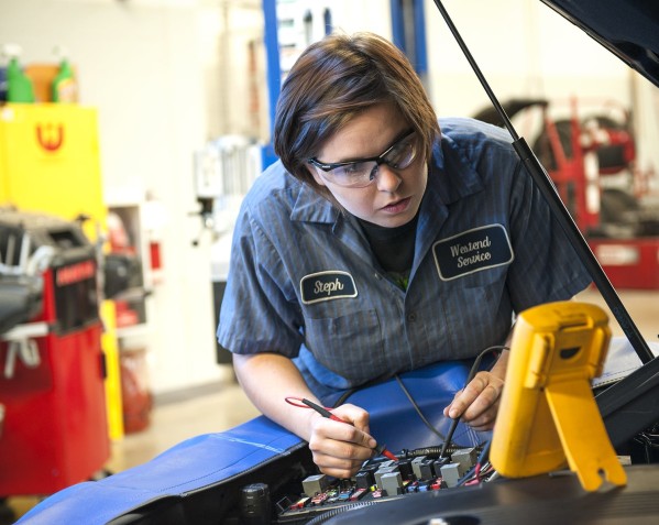person testing electronics under the hood of a car