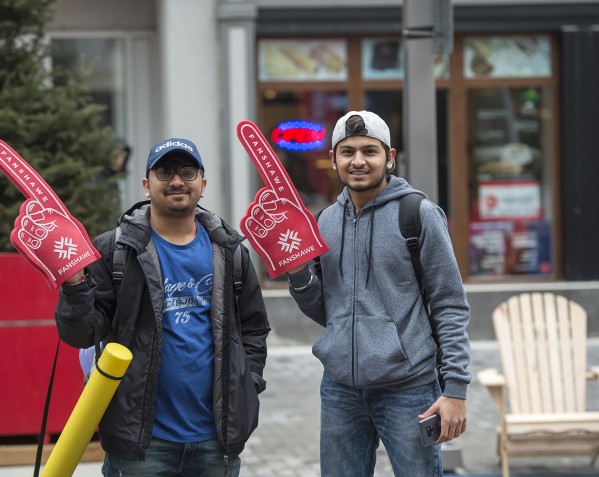 At the Fanshawe LIVE at Dundas Place event at the London Downtown Campus, two people stand outside holding red foam fingers with the Fanshawe logo.