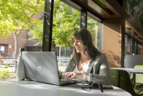 Photo of a student working on their laptop in a cafeteria