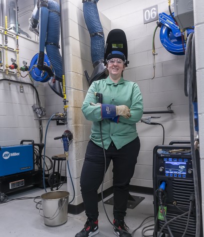 welding student stands wearing protective equipment by work station