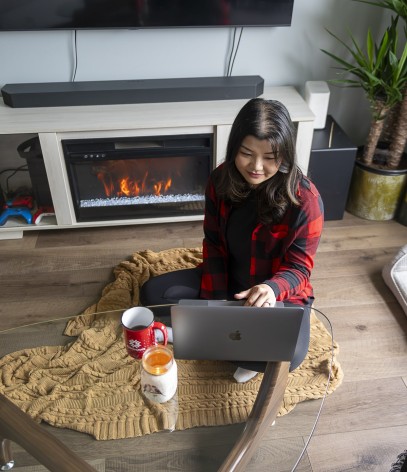 students sits by fireplace while studying on laptop