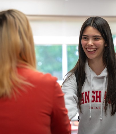 a student is shaking hand with a college staff