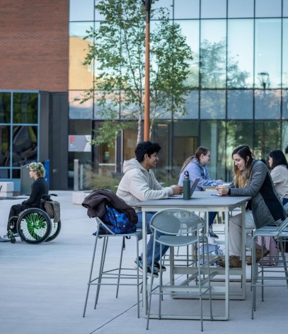 Fanshawe students sitting on raised tables within the Innovation Village courtyard