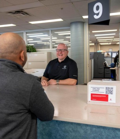 student talks to staff at office of the registrar desk